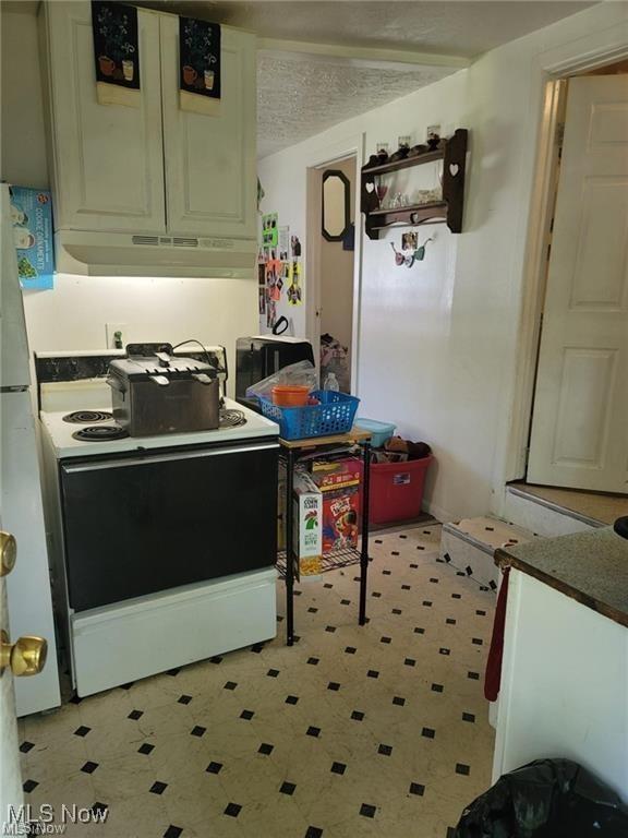 kitchen featuring light floors, white electric range oven, white cabinets, a textured ceiling, and under cabinet range hood