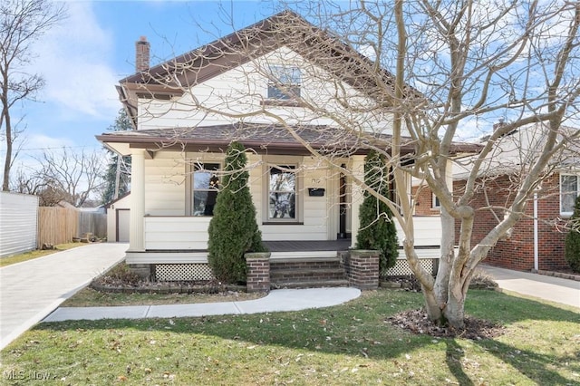 view of front of property with covered porch, a chimney, a front yard, and fence