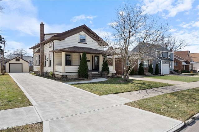 view of front of house featuring an outbuilding, a detached garage, a chimney, driveway, and a front lawn