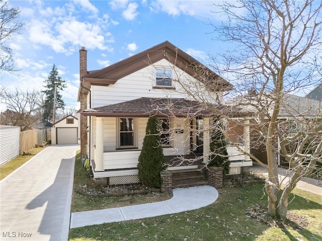 view of front of property featuring a chimney, fence, a detached garage, and an outbuilding