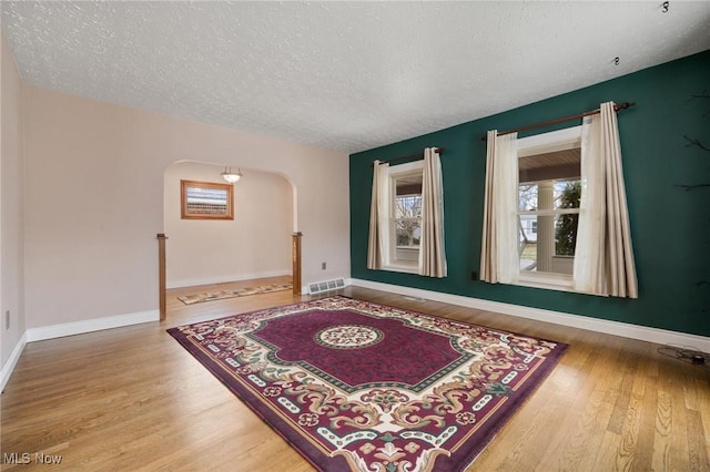 interior space featuring baseboards, visible vents, arched walkways, and wood finished floors