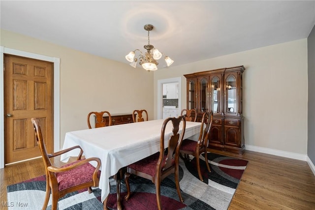 dining area with baseboards, a chandelier, and wood finished floors