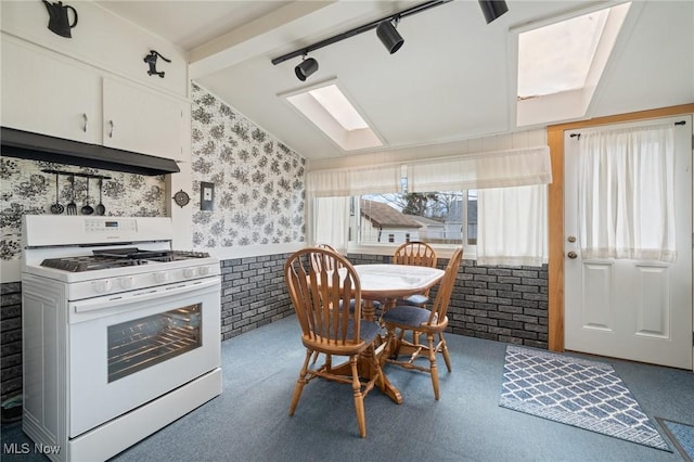 kitchen with white gas range, white cabinets, carpet flooring, vaulted ceiling with skylight, and under cabinet range hood