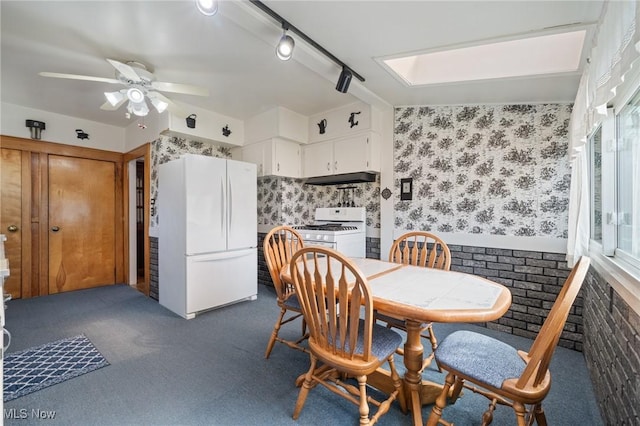 dining room with dark colored carpet, a ceiling fan, and wallpapered walls