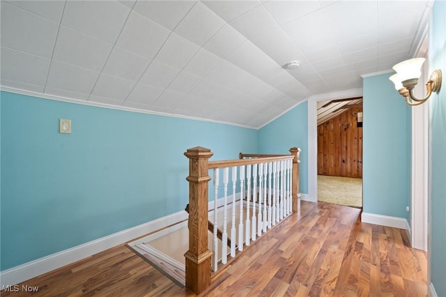 hallway with lofted ceiling, baseboards, wood finished floors, and an upstairs landing