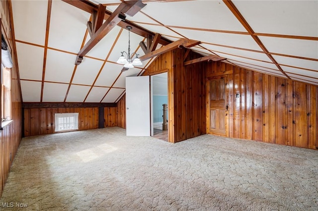 bonus room with carpet floors, wood walls, vaulted ceiling, and a notable chandelier