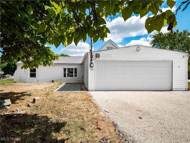 ranch-style home with gravel driveway and a garage