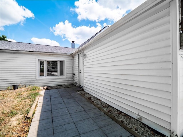 exterior space with a patio and roof with shingles