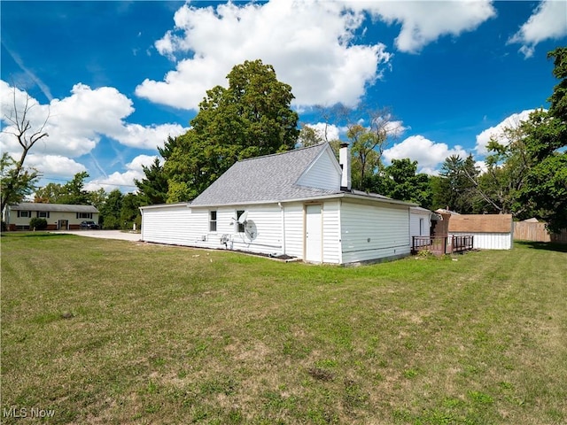 exterior space with a shingled roof, a chimney, and a yard