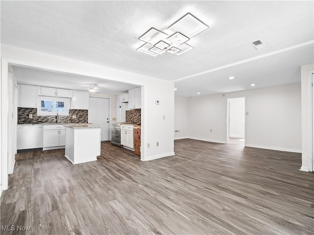 kitchen featuring dishwashing machine, a center island, white cabinetry, open floor plan, and decorative backsplash