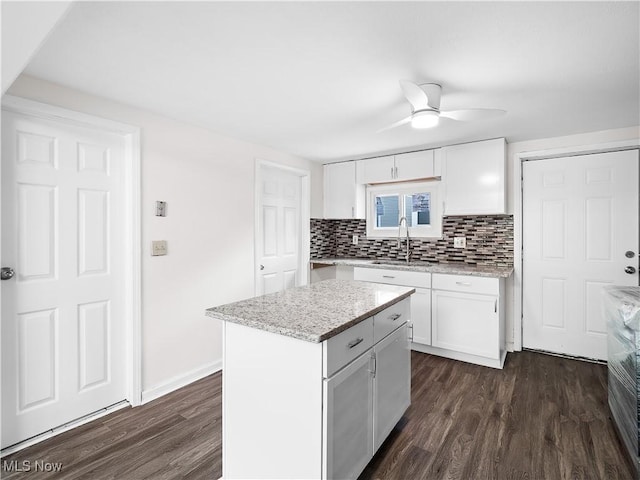 kitchen featuring white cabinets, tasteful backsplash, dark wood finished floors, and a sink