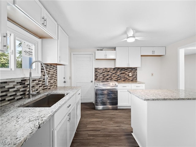 kitchen with decorative backsplash, electric stove, white cabinets, dark wood-style floors, and a sink