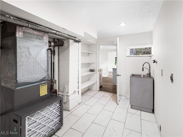 bathroom with marble finish floor, recessed lighting, a sink, and heating unit