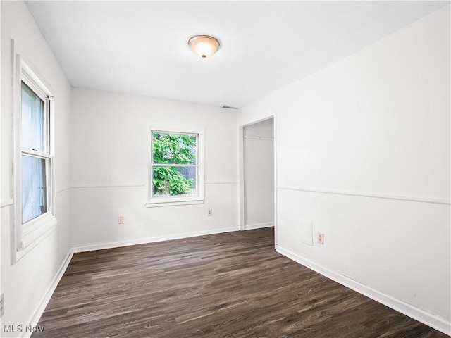 spare room with dark wood-type flooring and baseboards