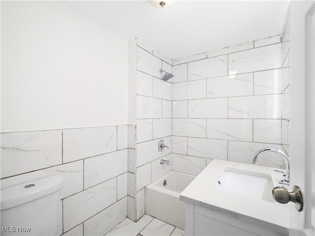 full bathroom with toilet, vanity, tile walls, marble finish floor, and washtub / shower combination