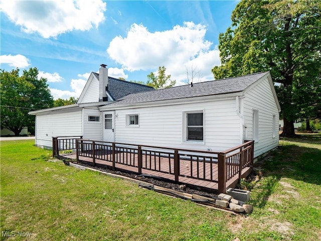 back of property with roof with shingles, a yard, a chimney, and a wooden deck