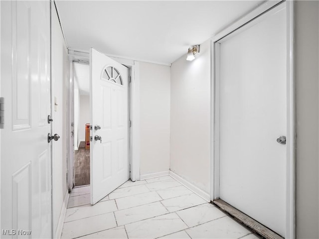 corridor featuring marble finish floor and baseboards