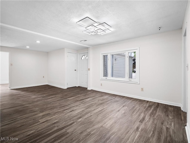 empty room featuring baseboards, dark wood finished floors, and a textured ceiling