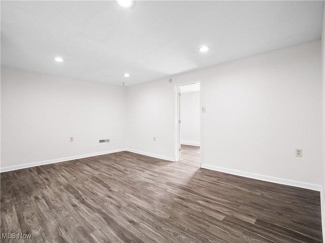 empty room featuring visible vents, baseboards, dark wood-style flooring, and recessed lighting