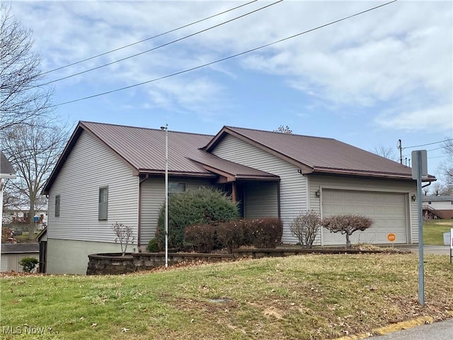 view of front of house featuring an attached garage, metal roof, and a front yard