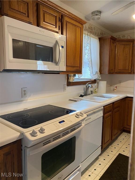 kitchen with white appliances, light countertops, and a sink