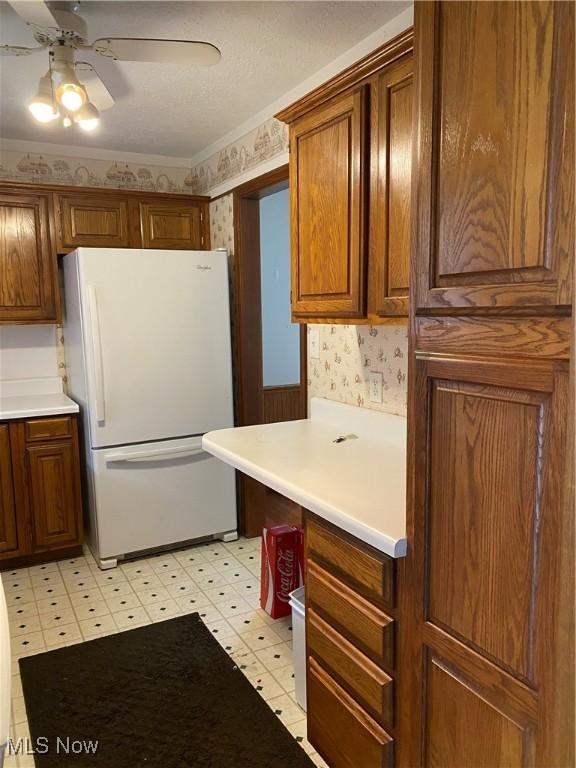 kitchen with ceiling fan, light countertops, freestanding refrigerator, light floors, and wallpapered walls