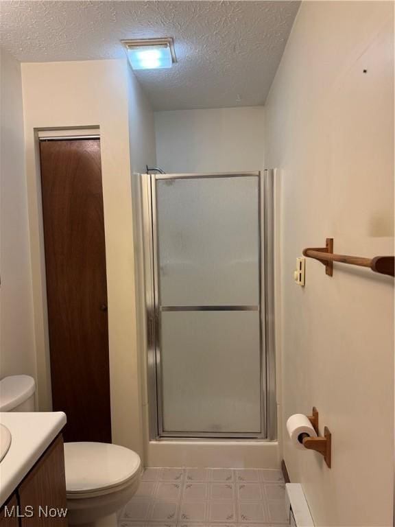 full bathroom with toilet, a stall shower, a textured ceiling, vanity, and tile patterned floors