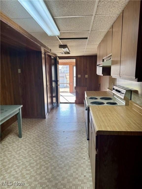 kitchen featuring light floors, electric range, wood walls, wood counters, and under cabinet range hood