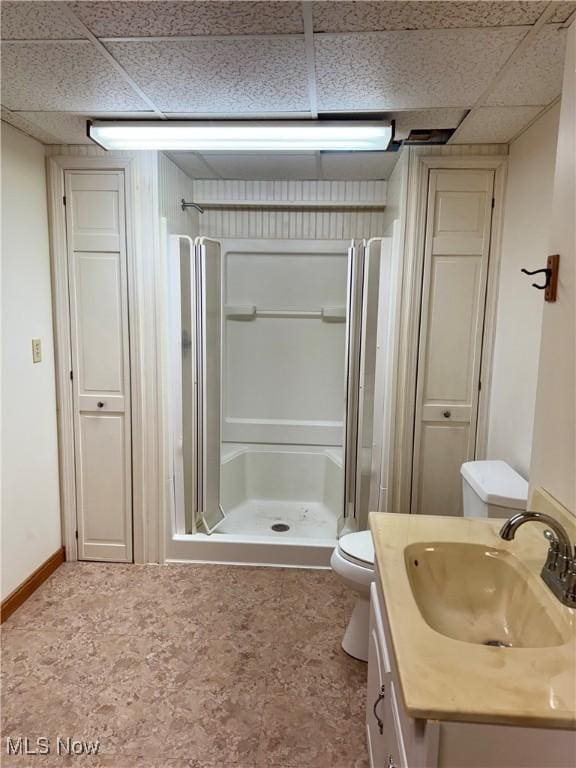 bathroom with a paneled ceiling, toilet, a shower stall, and vanity