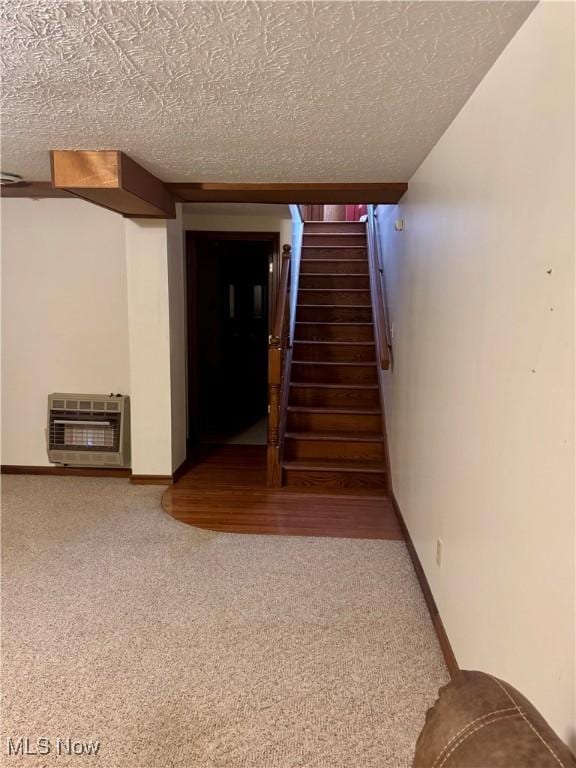 staircase featuring carpet, baseboards, a textured ceiling, and heating unit