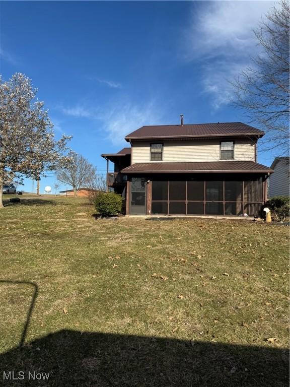 rear view of house with a lawn and a sunroom