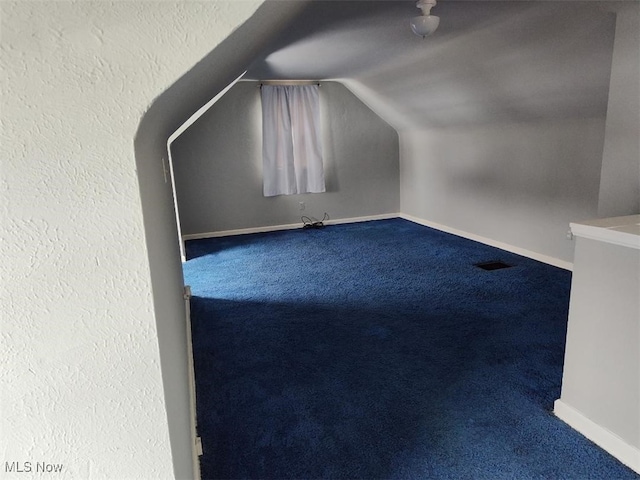 bonus room featuring carpet floors, visible vents, baseboards, and lofted ceiling