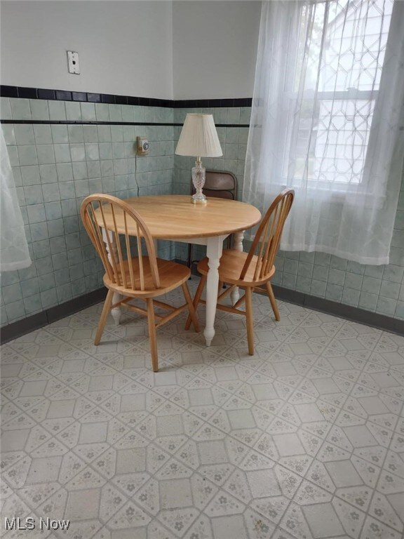 14504 Kennerdown Ave, Maple Heights, OH 44137 - dining room with light flooring, wainscoting, and tile walls