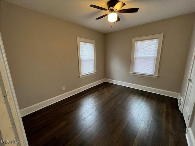 unfurnished room featuring dark wood-style flooring, a wealth of natural light, and baseboards