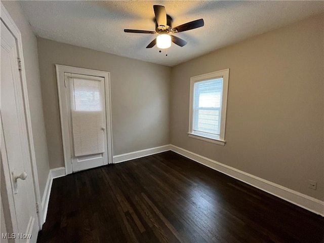 empty room with dark wood-style floors, ceiling fan, baseboards, and a textured ceiling