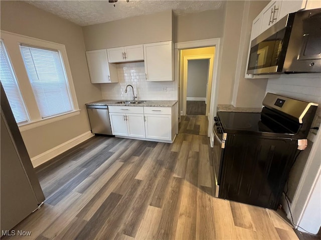 kitchen featuring tasteful backsplash, dark wood-type flooring, stainless steel appliances, white cabinetry, and a sink