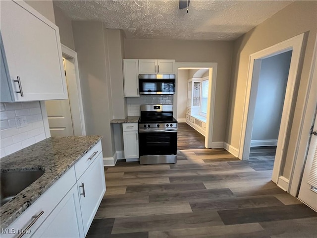 kitchen featuring appliances with stainless steel finishes, white cabinetry, a sink, and dark wood-style floors