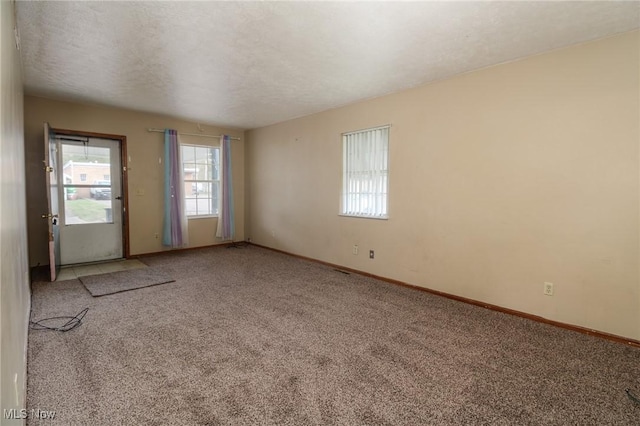 empty room featuring carpet, a textured ceiling, and baseboards