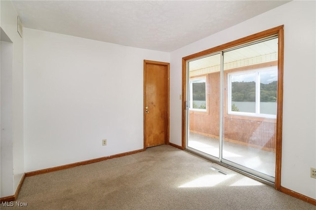 empty room with visible vents, a textured ceiling, baseboards, and carpet flooring