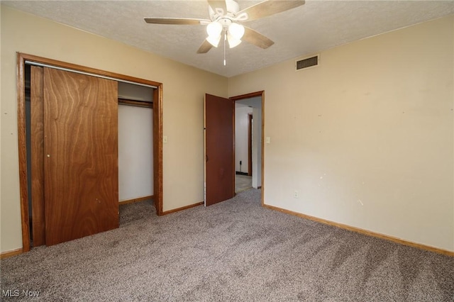 unfurnished bedroom with a textured ceiling, carpet flooring, visible vents, baseboards, and a closet