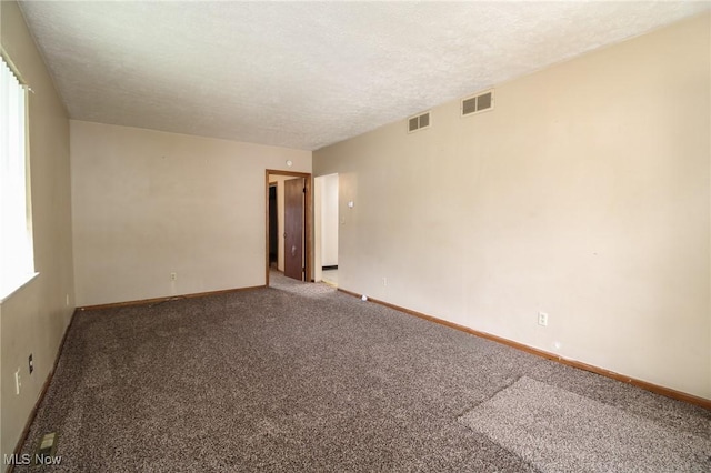 unfurnished room with baseboards, carpet, visible vents, and a textured ceiling