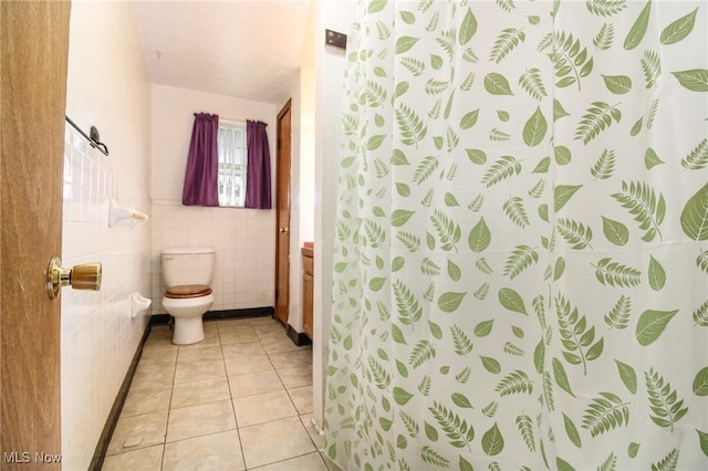 full bathroom featuring a shower with shower curtain, toilet, a wainscoted wall, tile patterned flooring, and tile walls