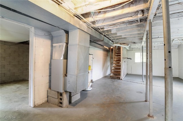 below grade area featuring concrete block wall, stairs, and water heater