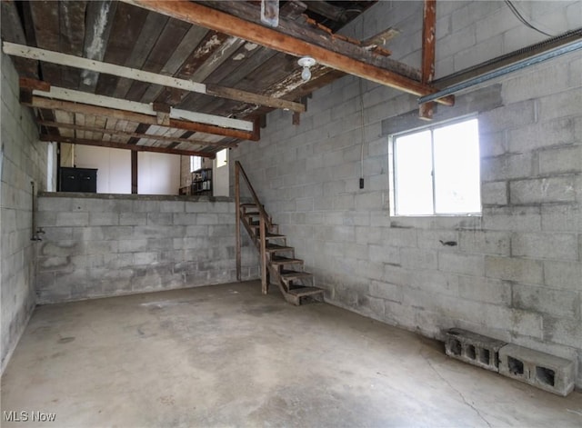 basement featuring stairway and concrete block wall