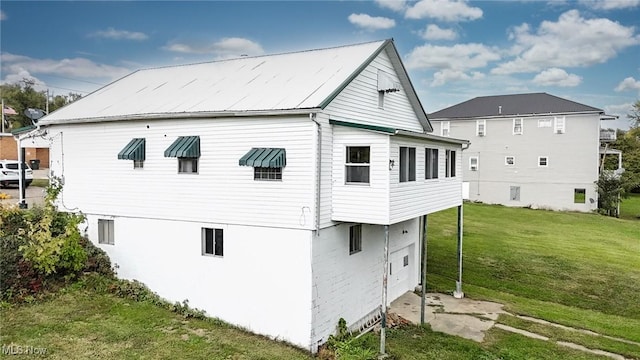 back of property with metal roof and a lawn