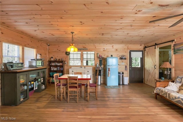 dining space with wood ceiling, wood finished floors, and a barn door