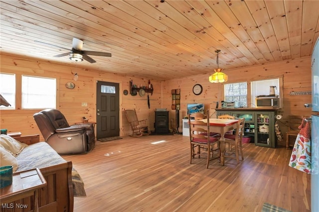 dining area featuring wood ceiling, a wood stove, wood walls, and wood finished floors