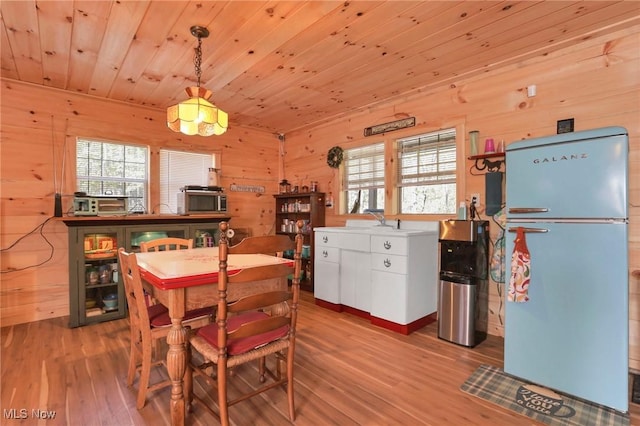 dining room with wood walls, wooden ceiling, and wood finished floors