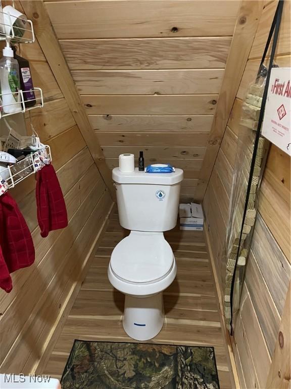 bathroom with wood walls and toilet