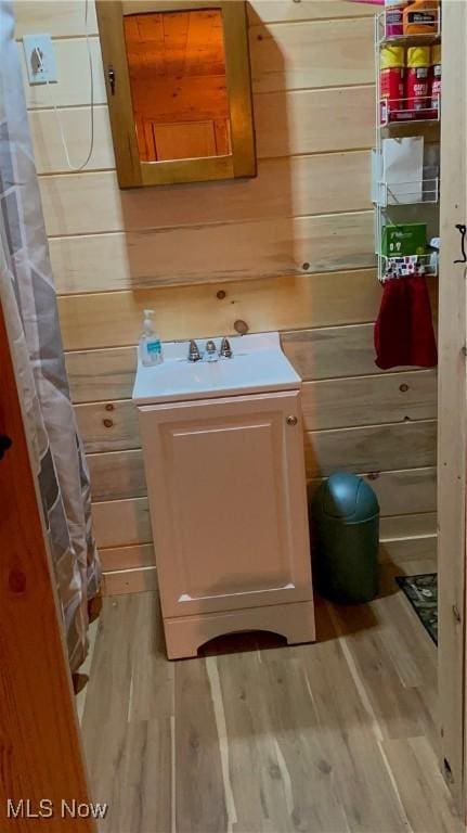 bathroom featuring wooden walls, vanity, and wood finished floors